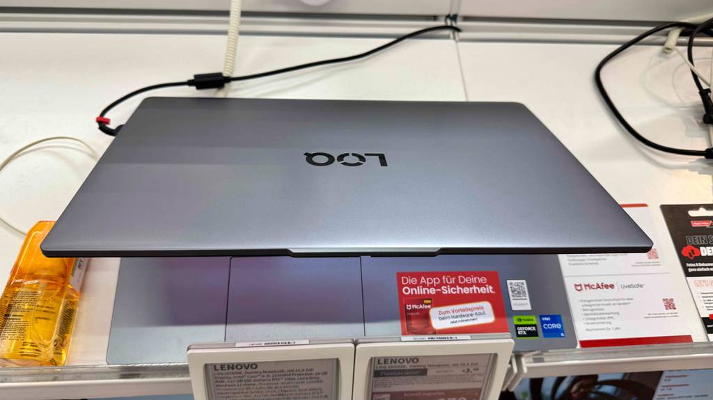 Das eingeschaltete Gaming-Laptop bis 800 Euro im Test steht leicht aufgeklappt auf einem Ausstellungstisch.
