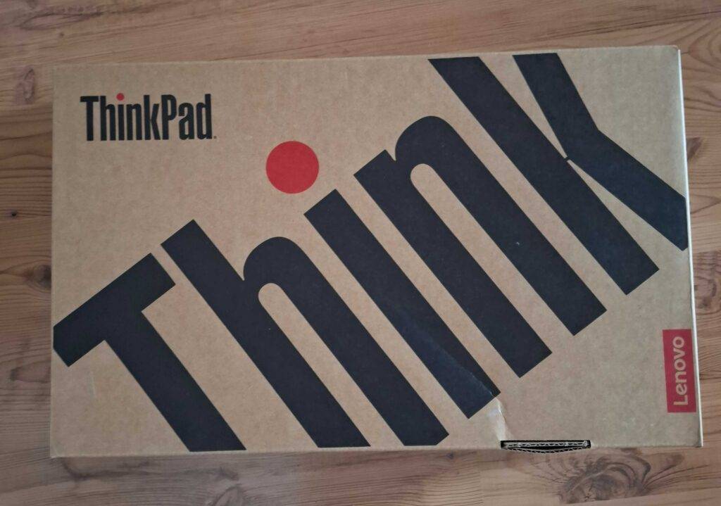 Der Verpackungskarton eines Lenovo-Laptop 14 Zoll im Test liegt auf einer Holzfläche.