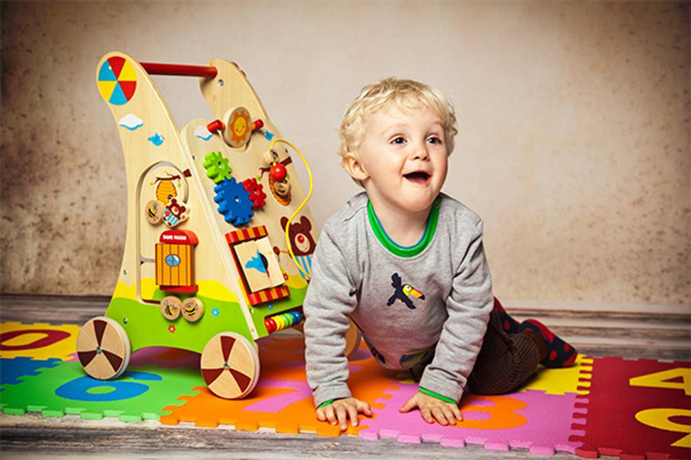 Lernspielzeug ab 1 Jahr im Test: Hier ein kleiner Junge auf einer Puzzlematte mit einem Lauflernwagen.