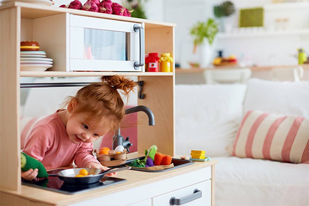 Lernspielzeug ab 2 Jahren im Test: Ein kleines Mädchen, das mit einer Kinderküche spielt.