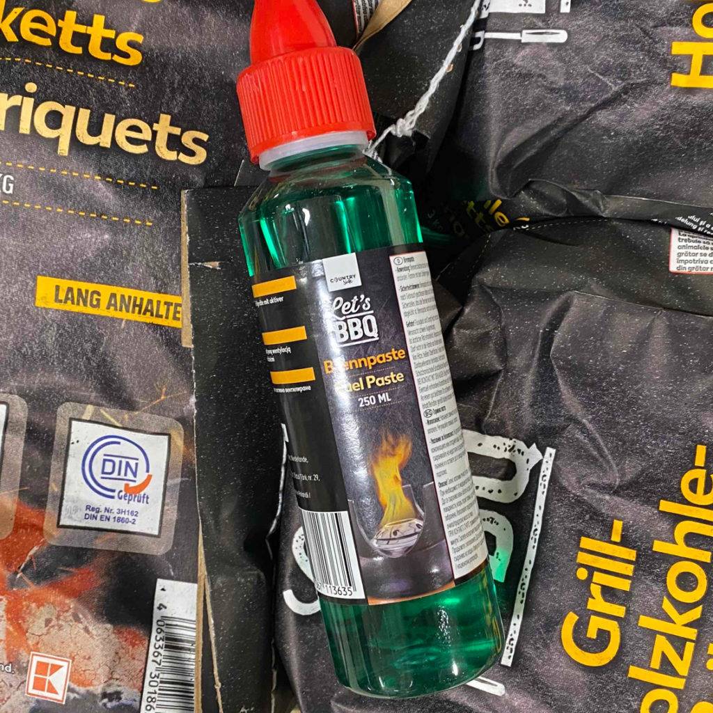 Brennpaste liegt auf Holzkohlepackungen.