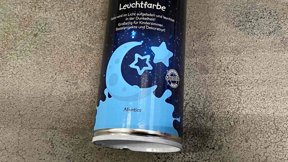 Nahaufnahme des Bodens einer Dose der getesteten Leuchtfarbe auf einem Betonboden.
