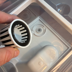 Zwei Finger halten einen kleinen Filter aus dem Levoit LV600S fest