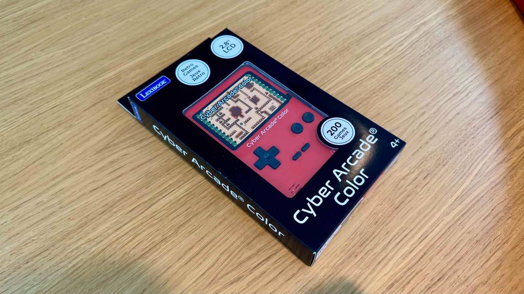 Eine rote Retro-Spielekonsole im Test liegt innerhalb der Verpackung auf einer Holzoberfläche.