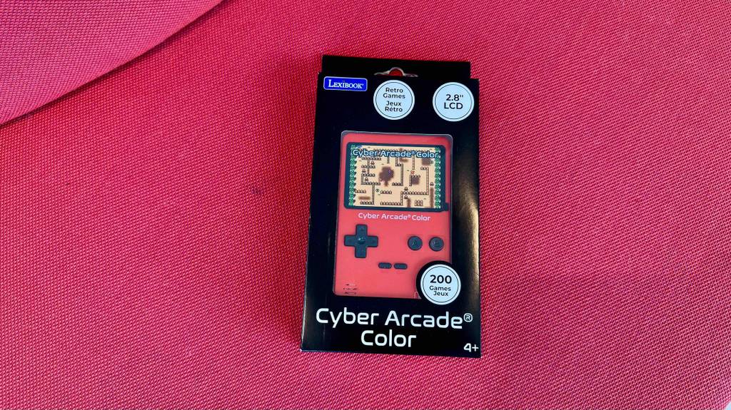 Eine rote Retro-Spielekonsole im Test liegt innerhalb der Verpackung auf einem roten Stoffbezug.