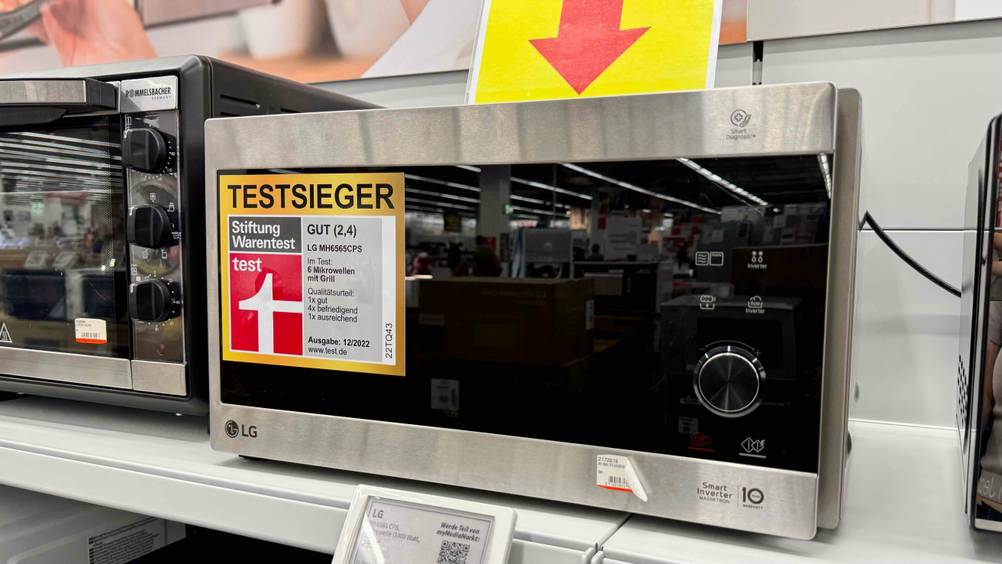 Die getestete LG-Mikrowelle auf einem Verkaufsregal zwischen anderen Geräten.