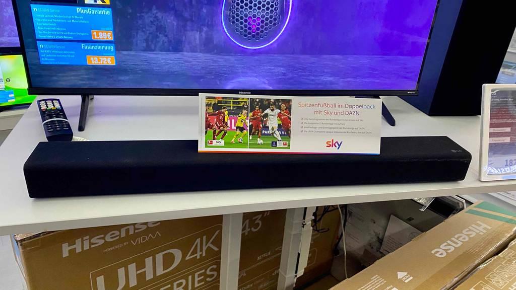 LG-Soundbar im Test: Ein Gerät steht mit einem Werbeplakat vor einem Fernseher .