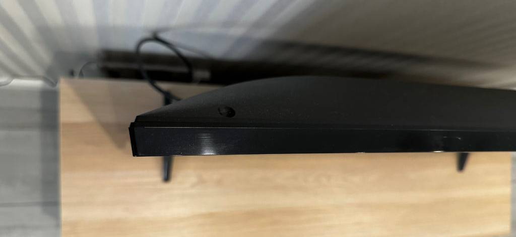 Ansicht von oben auf einen schwarzen LG-Fernseher im Test, der auf einem Holzregal steht.