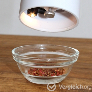 Licht an Pfeffermühle in Nahansicht über einem Schälchen mit gemahlenem Pfeffer