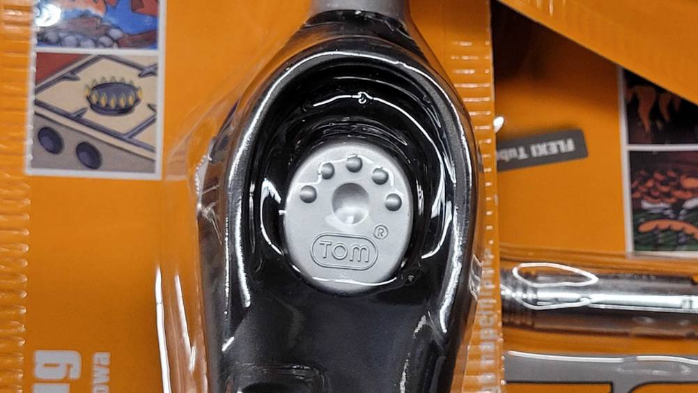 Nahaufnahme des Bedienelementes eines Lichtbogen-Feuerzeuges im Test in seiner transparenten Verpackung.