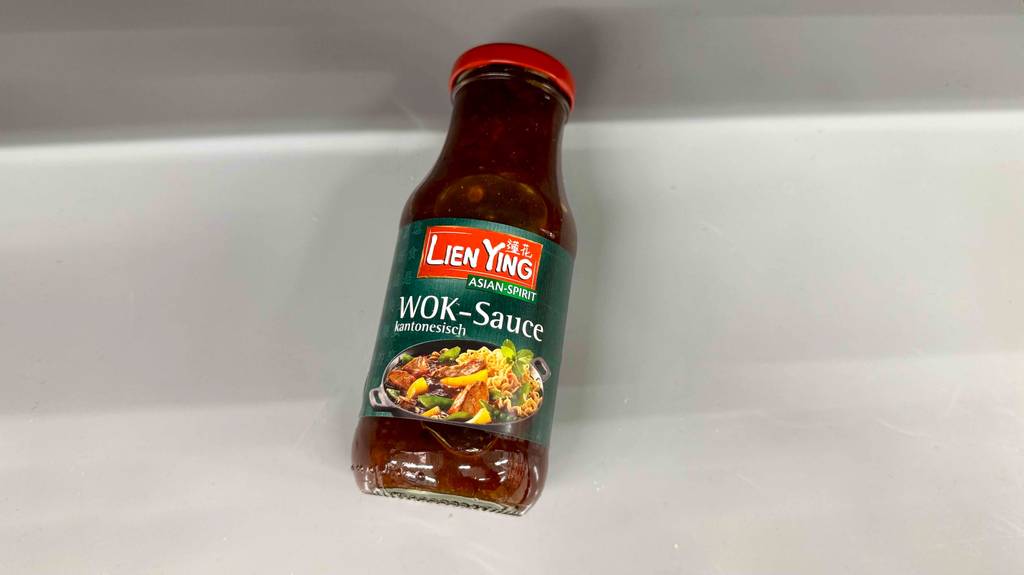 Asia-Wok-Saucen im Test: Eine Glasflasche mit Schraubverschluss liegt auf einer weißen Oberfläche.