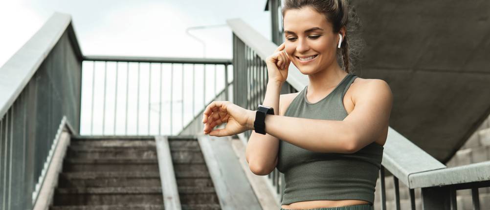 LIGE-Smartwatches im Test: junge Frau, die im Rahmen ihres Workouts vor einer Treppe steht und auf Ihre Smartwatch schaut