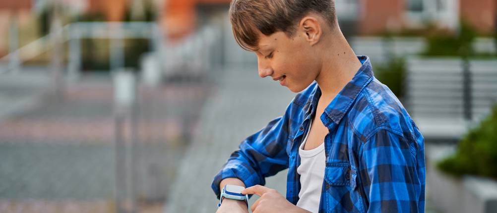 LIGE-Smartwatches im Test: Junge in kariertem Hemd, der auf seine Smartwatch schaut
