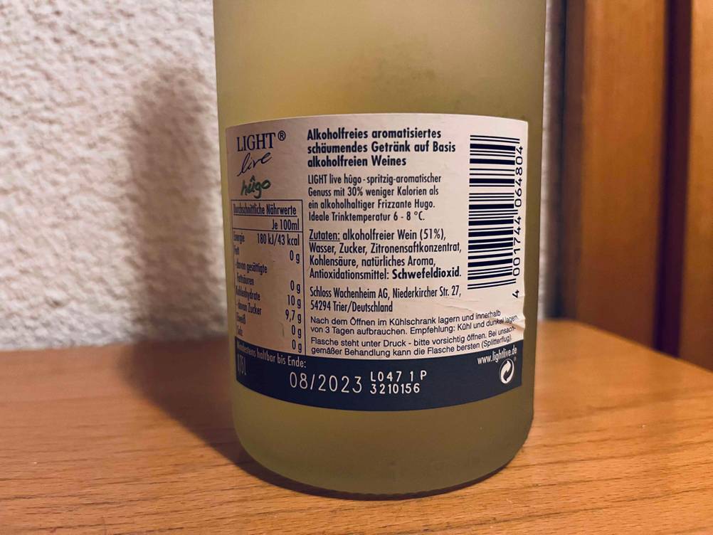 Alkoholfreier Sekt im Test: unterer Teil einer Flasche mit rückwärtigem Etikett und Beschreibung des Getränks.