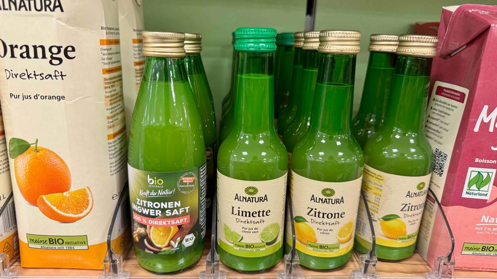 Mehrere Flaschen des getesteten Limettensafts in einem Verkaufsregal neben anderen Produkten.