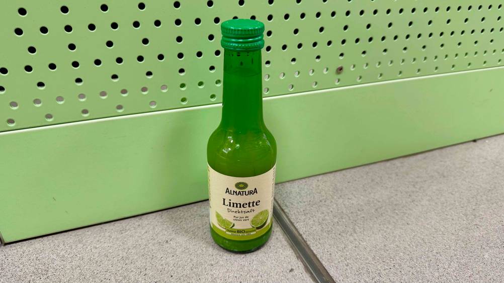 Limettensaft im Test: Eine Flasche vor einer grünen Wand.
