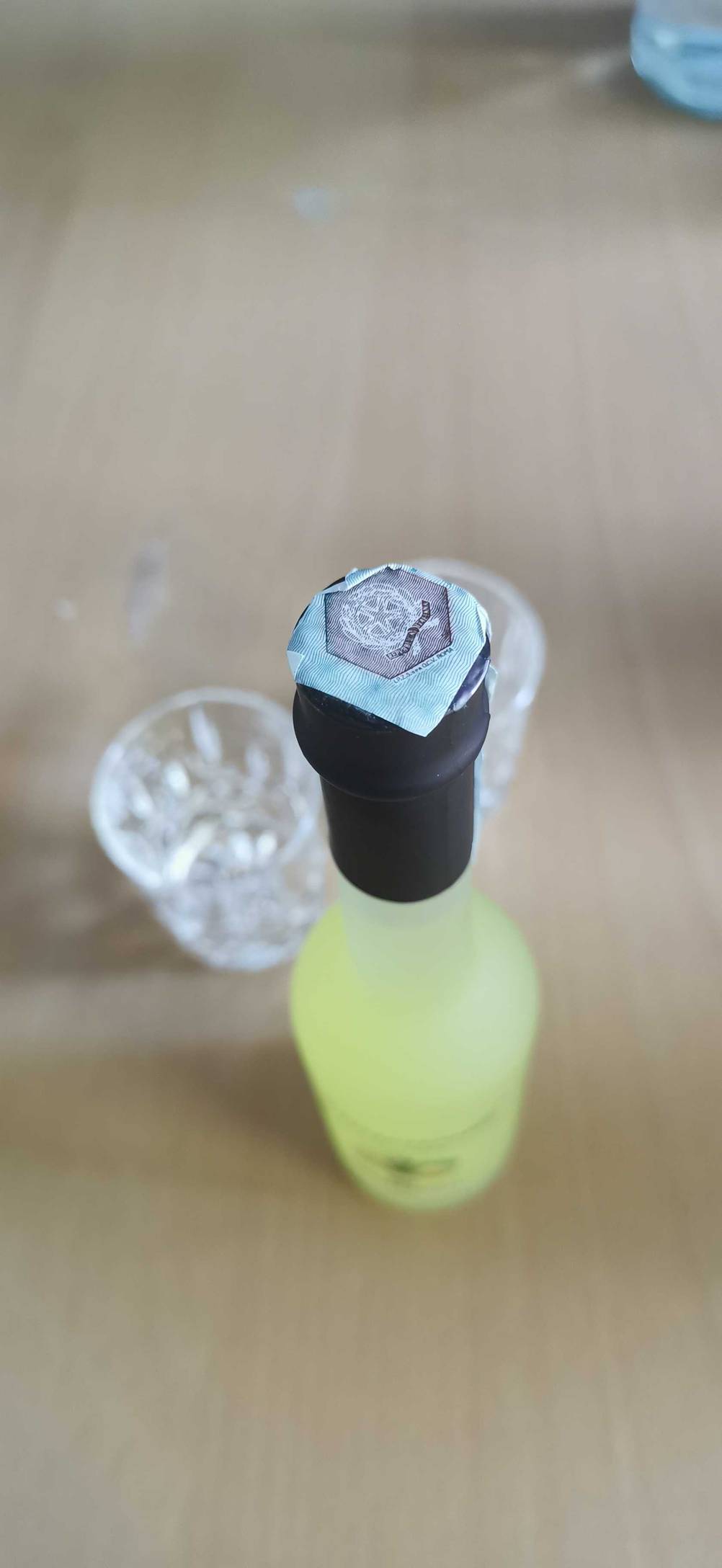 Nahaufnahme der Verschlusskappe einer Flasche des getesteten Limoncellos, im Hintergrund zwei Gläser.