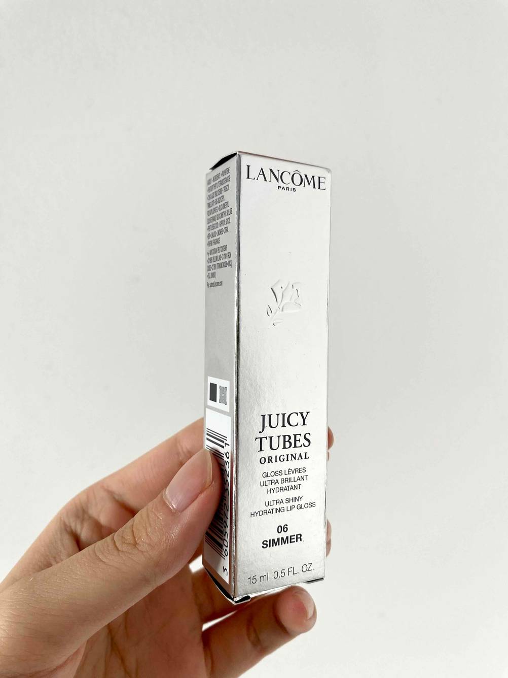 Eine Hand hält eine Verpackung des getesteten Lippenstiftes vor eine helle Fläche.