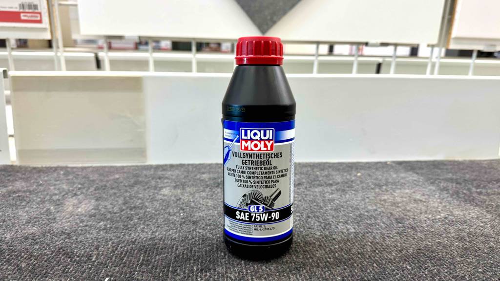 Im Test: 75W90-Öl für Getrieb in der Kunststoffflasche steht auf einem grauen Teppichboden.