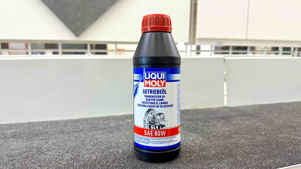 Getriebeöl im Test: Eine schwarze Kunststoffflasche steht auf einem Teppichboden.