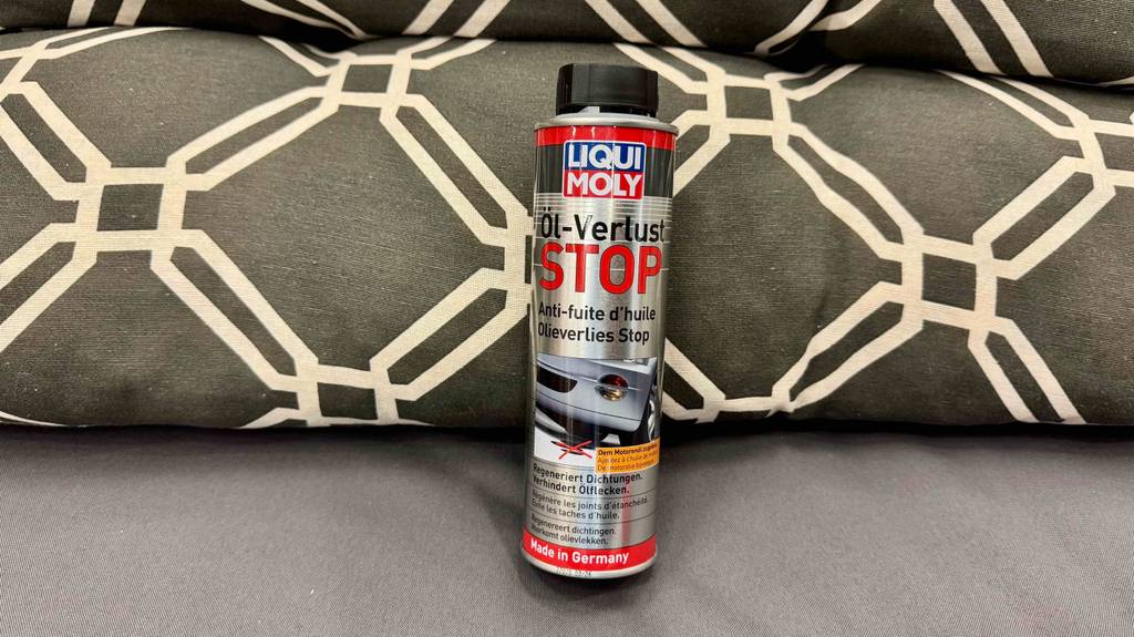 Eine Sprühflasche mit dem getesteten Öl-Verlust Stop steht auf einem Sofa.
