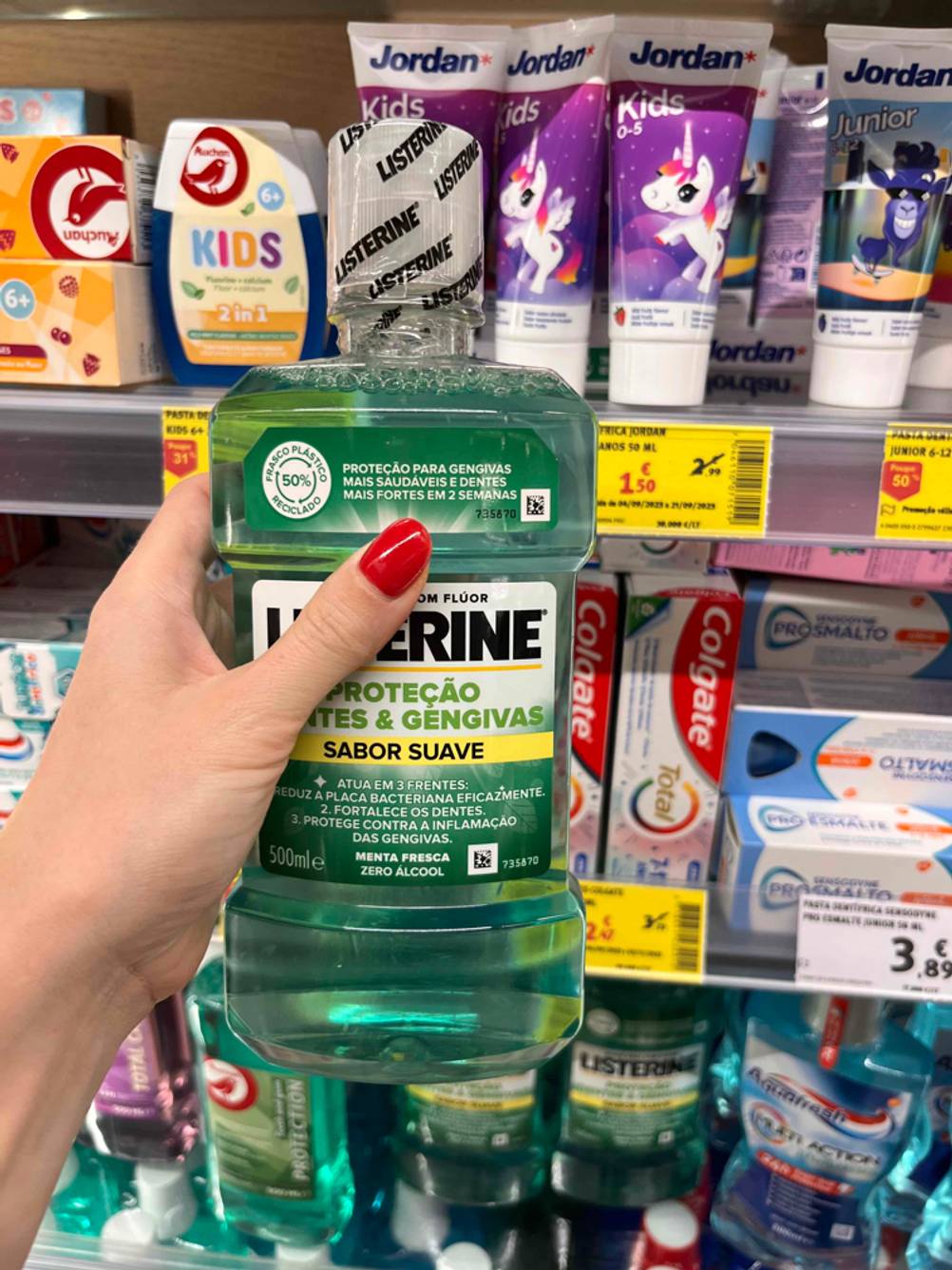 Im Test: Eine Hand hält eine Flasche Listerine-Mundspülung vor einem Drogerieregal.