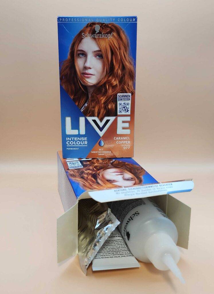 Haarfärbemittel-Test: Eine geöffnete Packung von Schwarzkopf inklusive mehrerer Komponenten liegt unter einer weiteren stehenden Verpackung.