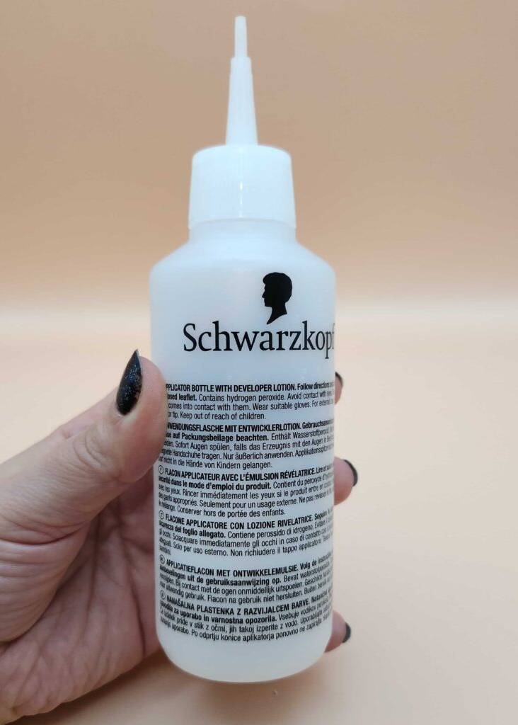 Eine Hand hält eine Quetschflasche mit Pipette, in der sich ein getestetes Haarfärbemittel befindet.
