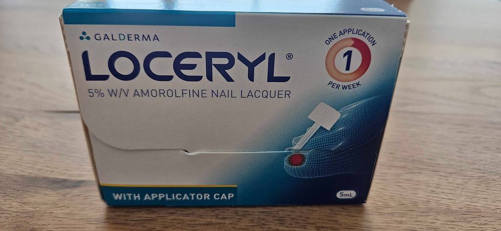 Loceryl-Mittel gegen Nagelpilz im Test in seiner weiß-blauen Verpackung auf Holz.
