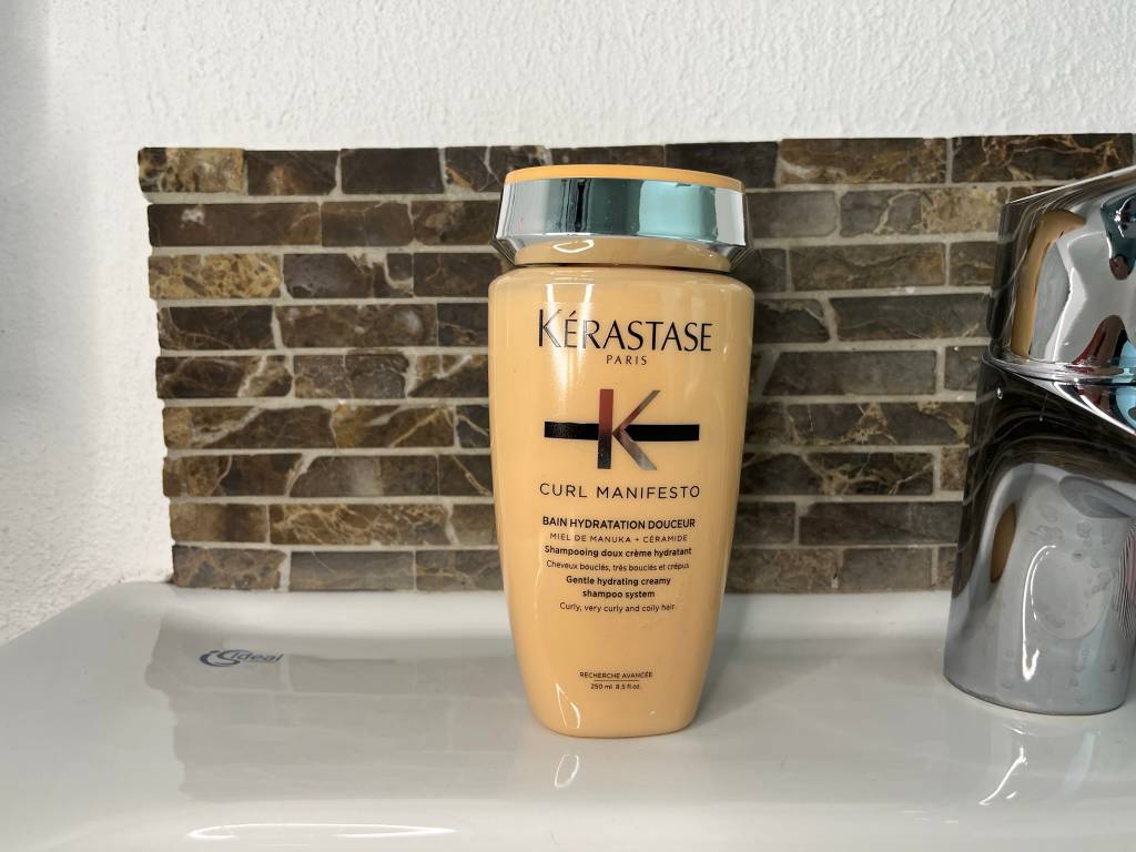 Locken-Shampoo steht auf Waschbeckenrand.