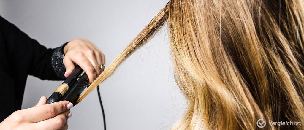 Glätteisen im Test glättet blonde Haare einer Frau. 