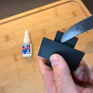 Mit einem Messer wird ein mit Loctite 401 verklebtes Stück Plastik angeschnitten