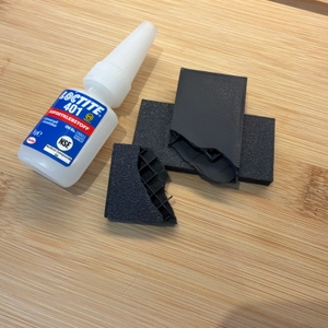 Ein zerbrochenes Stück Plastik liegt neben dem Loctite 401