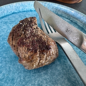 Fertiges Steak mit etwas Salz auf einem blauen Teller