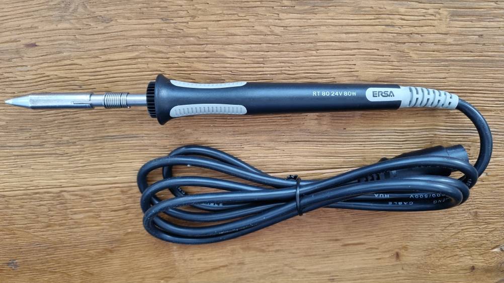 Lötkolben mit Kabel liegt auf Untergrund