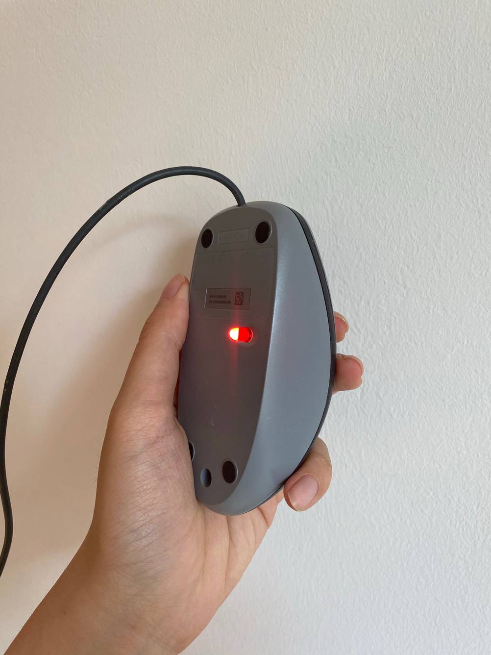Eine graue Computer-Maus von unten. Der Laser ist zu sehen.