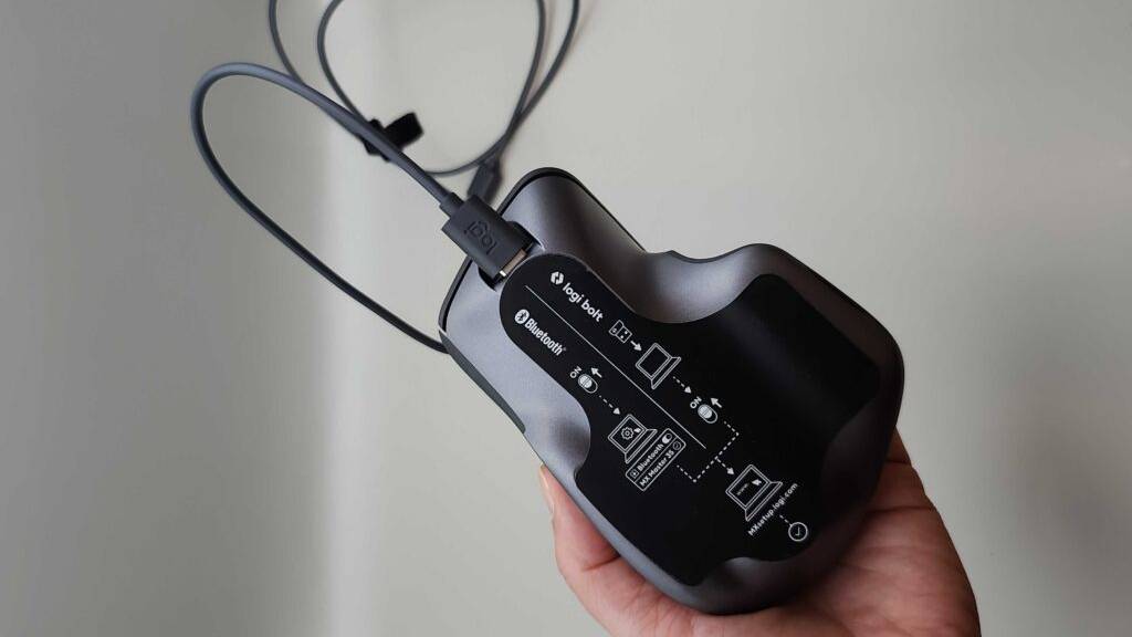 Eine Hand zeigt die Unterseite inklusive bedruckter Gebrauchstipps einer schwarzen ergonomischen Maus im Test.