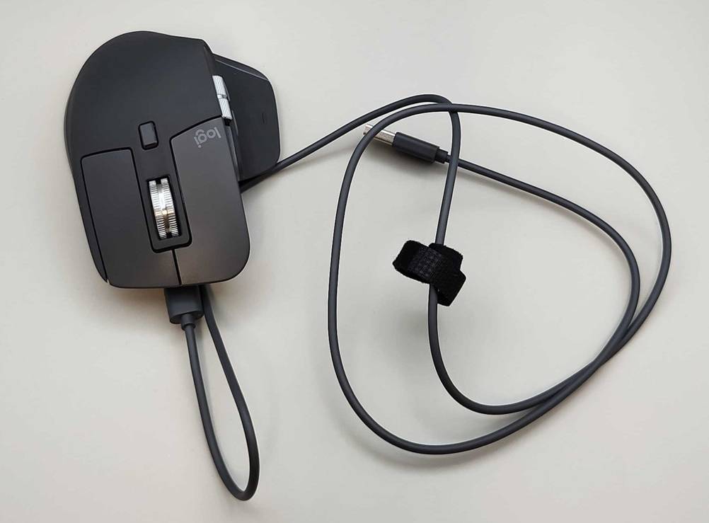 Eine kabelgebundene, getestete ergonomische Maus befindet sich von oben gesehen auf einer weißen Oberfläche.