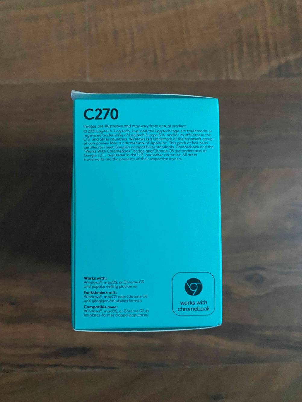 Verpackung von einer getesteten Logitech-Webcam befindet sich auf einem Holztisch. 