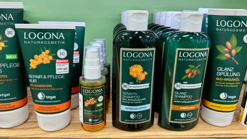 Mehrere Flaschen des Logona-Shampoos im Test auf einem Verkaufsregal neben anderen Produkten.