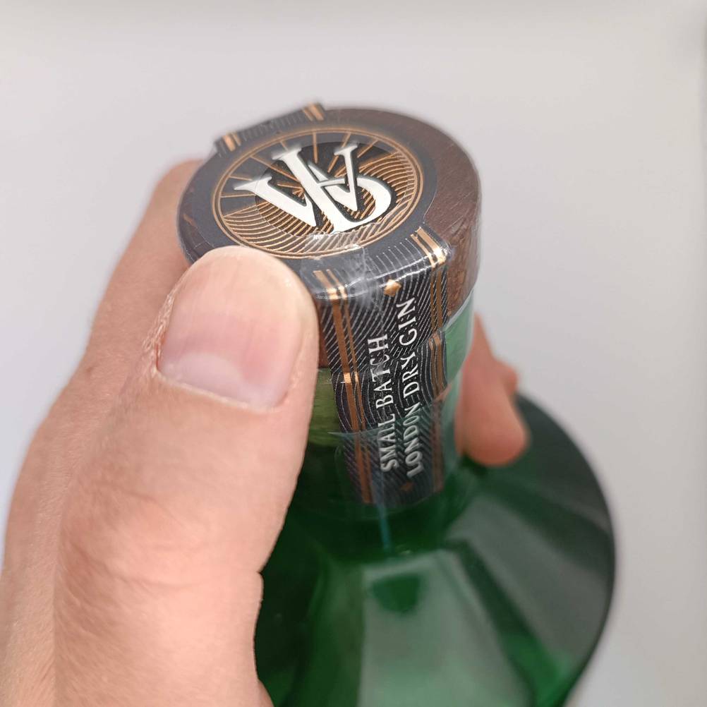 Ein Daumen an der Verschlusskappe eines getesteten London-Dry-Gins.