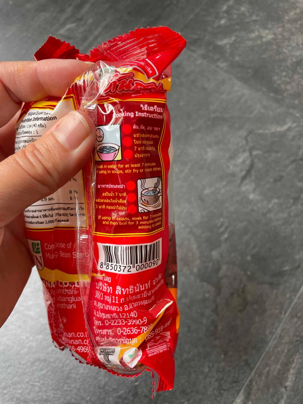Im Test: Nahaufnahme der Zubereitungsinstruktionen auf der Rückseite einer Packung Glasnudeln die eine Hand vor eine dunkle Fläche hält.