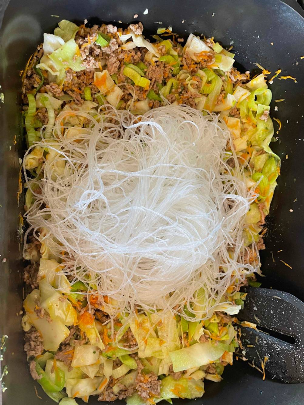 Getestete Glasnudeln liegen in einer Schale auf Hackfleisch mit Gemüse.