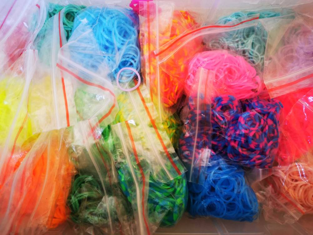 Viele unterschiedlich farbige Loom-Bänder im Test in kleinen Tüten.