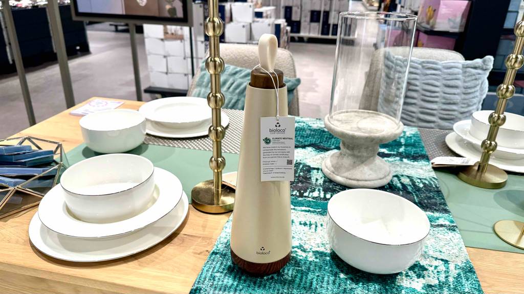 Auf einem Ausstellungstisch im Geschäft steht eine getestete Edelstahl-Trinkflasche in Beige.