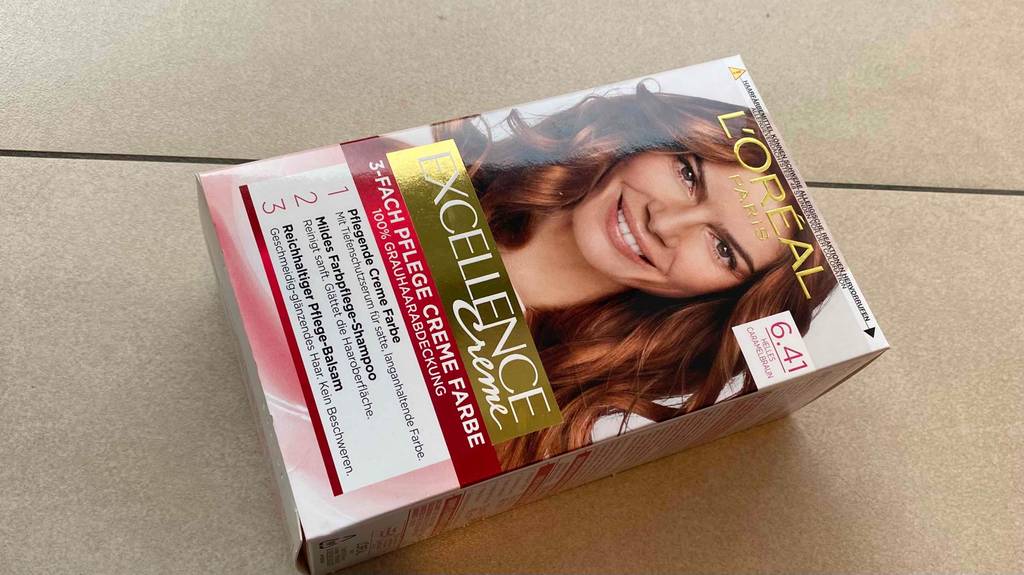 Im Test: L’Oréal Haarfarbe Excellence Creme in der Farbkombination 6.41 liegt schräg auf hellem Hintergrund.