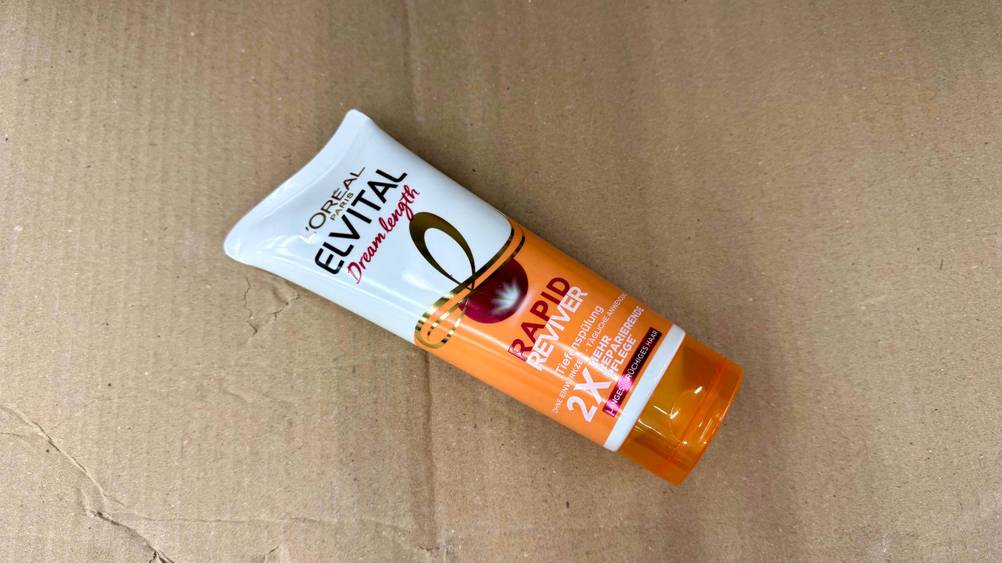 Auf einem Karton liegt horizontal eine Tube der getesteten L'Oreal-Haarkur.