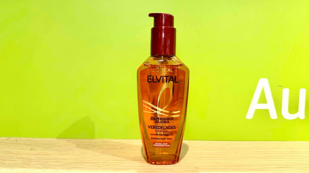 Eine Flasche Loreal-Haarpflege steht zum testen vor einer grünen Wand.