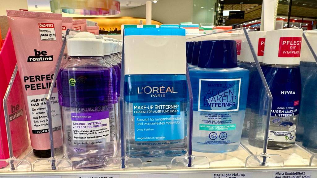 Eine Quetschflasche mit getestetem Make-Up-Entferner steht neben anderen Augenpflegeprodukten in einem Verkaufsregal.