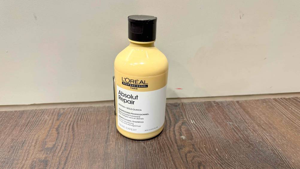 Vor einer grauen Wand am Boden steht das getestete L'Oréal-Professional-Shampoo.